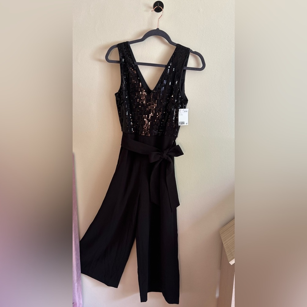 H&M BLACK ROMPER WITH SEQUINS ON TOP. V-CUT IN FRONT AND BACK. NEVER WORN TAG ON